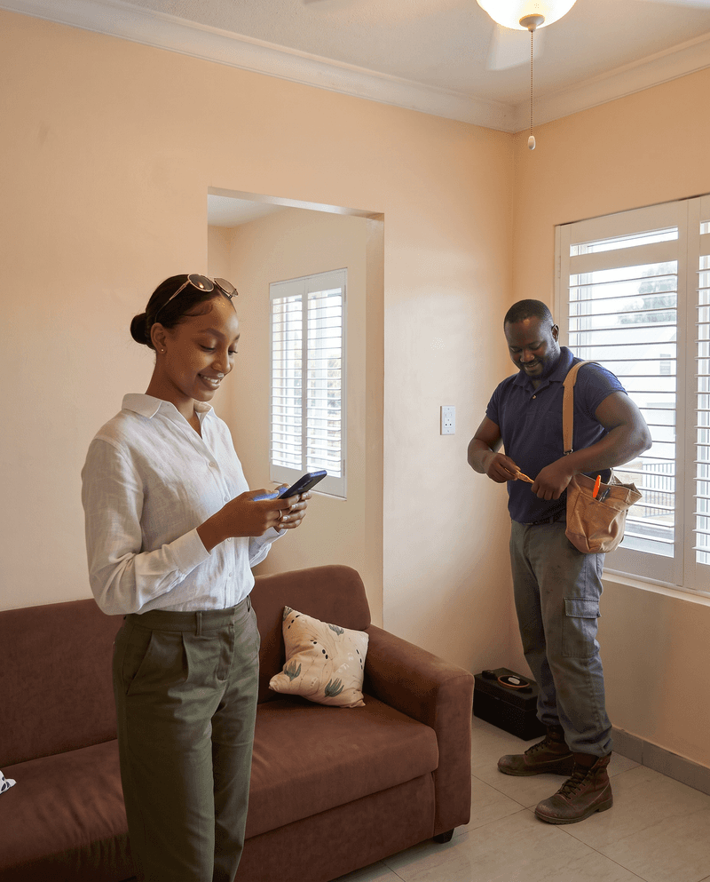 A client checks her phone while a worker packs up after the job